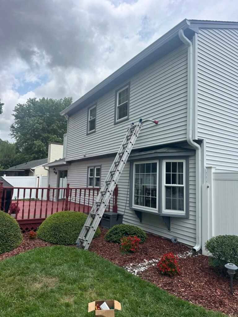 Expert installers fitting seamless gutters on two-story house