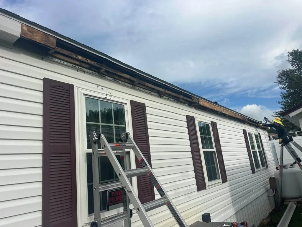 Severely damaged fascia board being removed and repaired before installing new seamless gutters