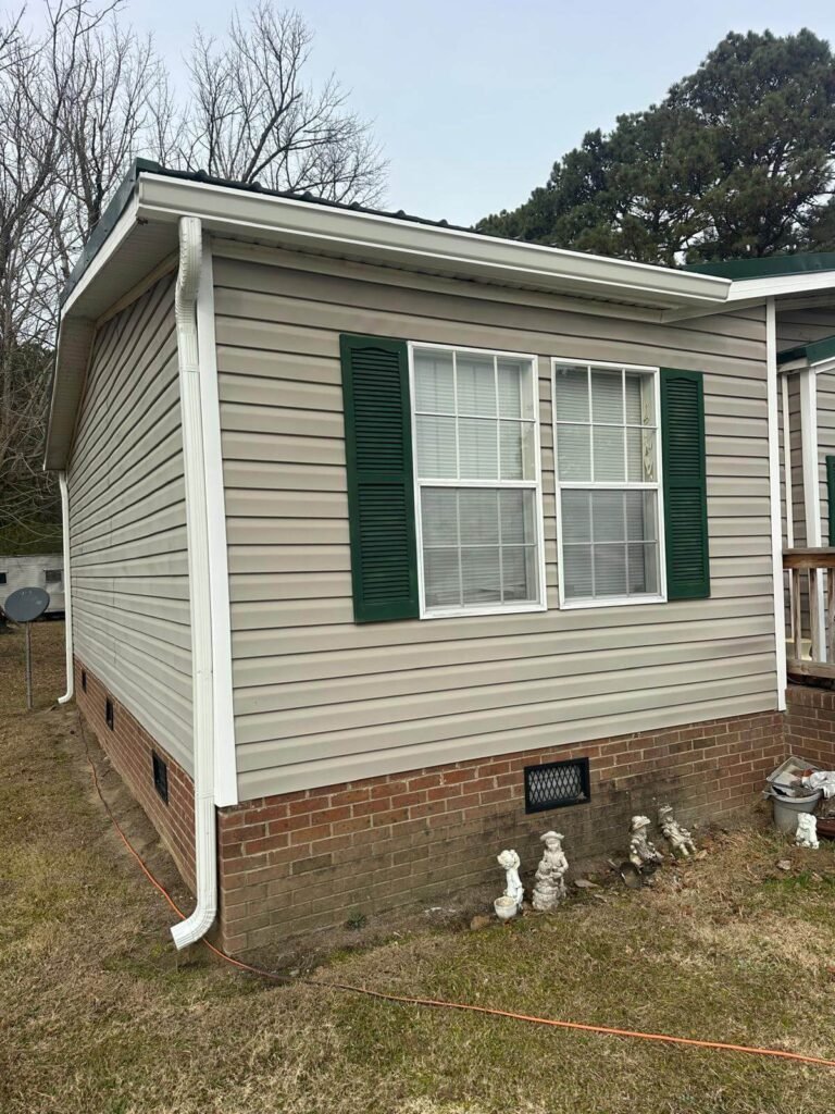 Seamless gutter installation on residential home in Conway NC with white aluminum gutters and downspout