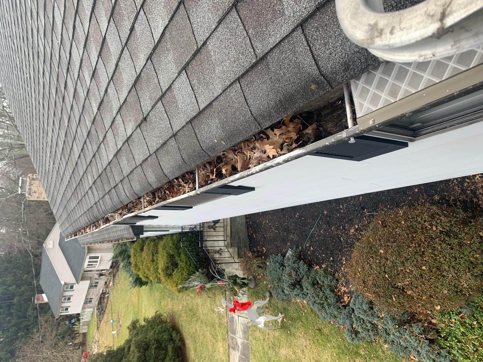 Clogged gutters overflowing with leaves on a Virginia Beach home