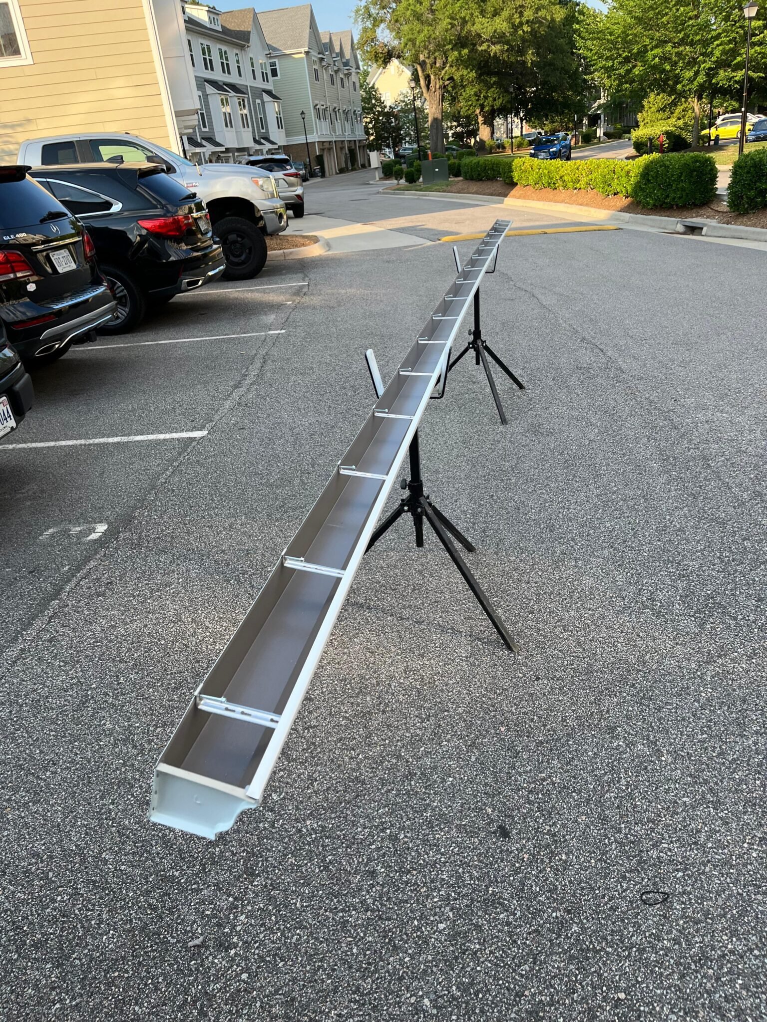 On-site fabrication — Full 200 ft extruded aluminum seamless gutter section formed and propped in the parking lot. Downspout outlet punched, end caps fitted, hidden hanger positioned — all at ground level before the section went up.