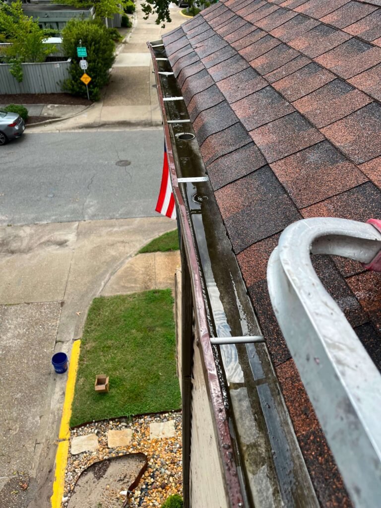 Standing water in a clogged second-story gutter before cleaning in Virginia Beach