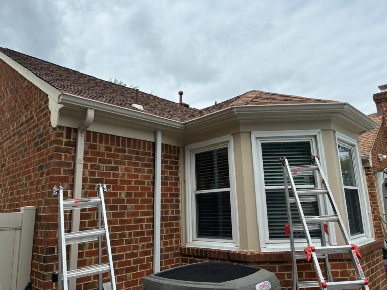 Existing gutters and downspouts on the rear roofline before fascia wrap installation in Chesapeake, VA