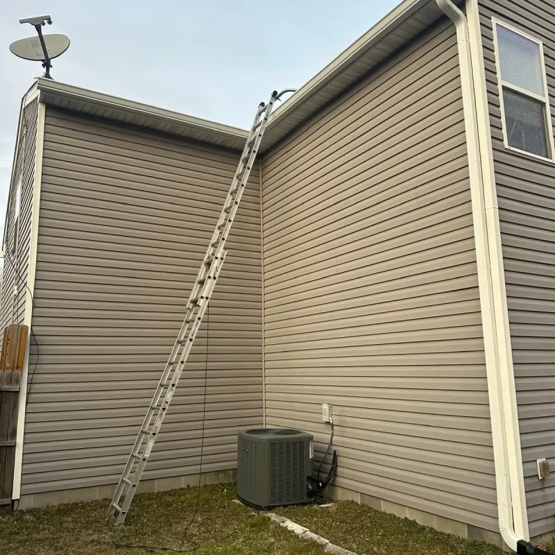 Newport News home gutter installation – technician using ladder to install durable gutter system.
