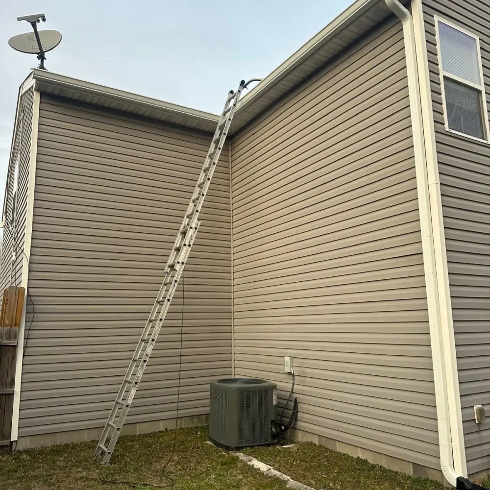 Newport News home gutter installation – technician using ladder to install durable gutter system.