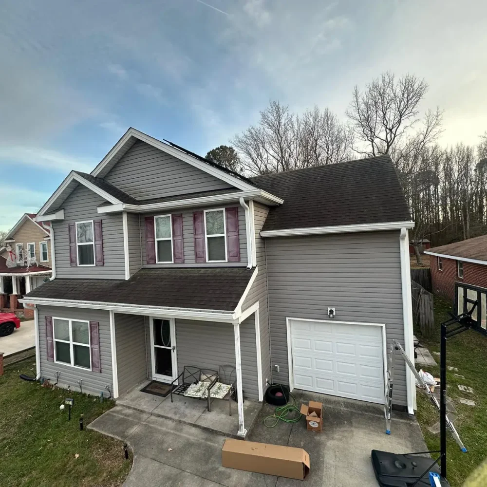Two-story suburban house with newly installed gutters and downspouts, showcasing professional gutter installation by Gutter Masters.