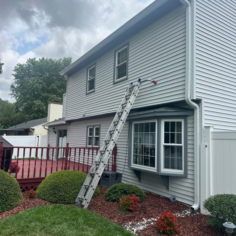 Expert installers fitting seamless gutters on two-story house