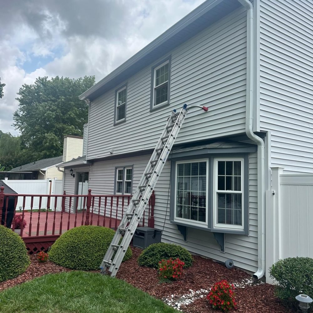 Expert installers fitting seamless gutters on two-story house