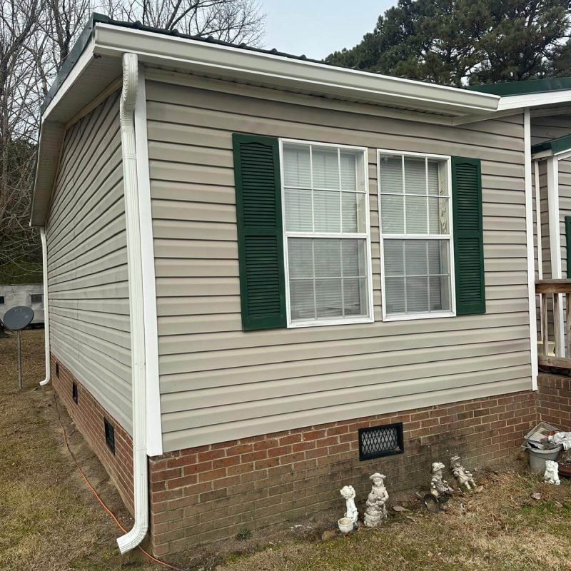 Seamless gutter installation on residential home in Conway NC with white aluminum gutters and downspout