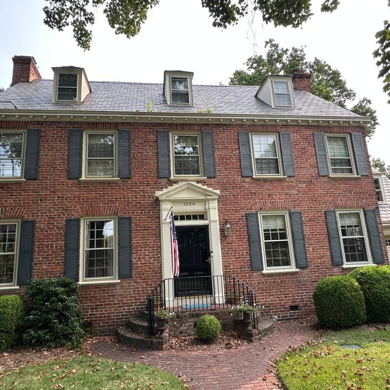 gutter cleaning and repair in progress on historic Georgian brick home Baldwin Avenue Norfolk VA 23507 — ladder positioned on roofline
