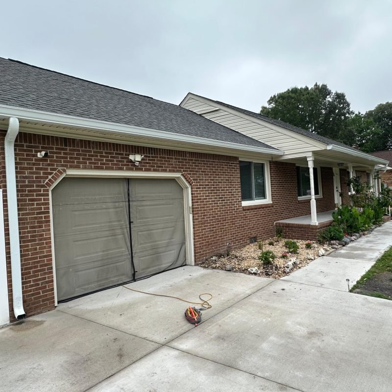 new white aluminum seamless gutter installed on garage roofline with downspout — Chesapeake VA after gutter replacement